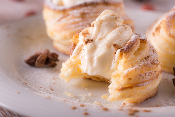 Sweet dessert from puff pastry filled by curd cheese on wooden board