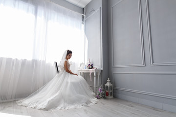 stylish bride sitting on a chair in room
The bride in a chic dress with  in the hotel room
 morning bride in the room with a light stylish interior