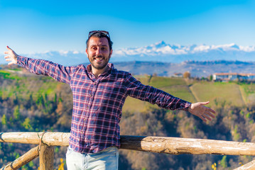 happy man tourist looking amazing green vineyards in the italian region of Piedmont, Alba, Langhe and Monferrato region, Italy. Alps mountain in background