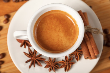 White espresso Cup on the background of coffee beans, cinnamon, anise. Fresh dark black strong Americano coffee on wooden table, thick foam in coffee, morning refreshing hot drink caffeine, top view