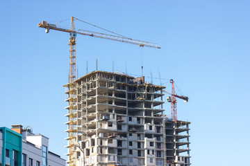 Construction site with yellow crane on blue sky background. Construction, construction work, lifting heavy loads up