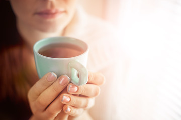 drinking tea sitting on the window of Caucasian beautiful middle-aged woman with red hair, toning