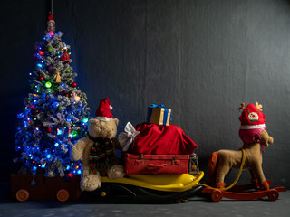 Sleigh of Santa Claus, bag with gifts, Christmas tree, Christmas toys and luminous garlands. Rocking horse depicting a deer