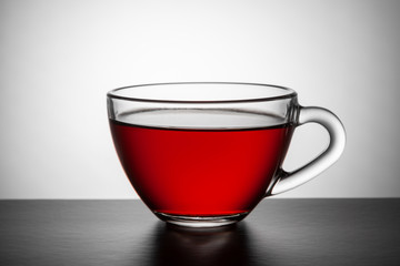  A transparent glass cup of tea stands on the table.