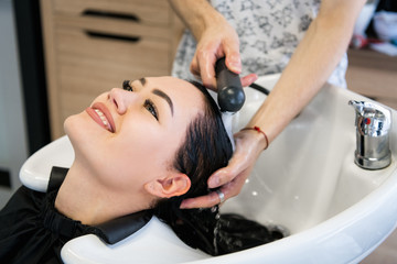Obraz na płótnie Canvas Beautiful young girl enjoying hair washing in hairdressing salon.