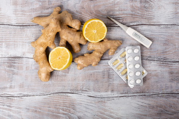 Treatment of cold and viruses. Be healthy.Healthy concept. Tea, lemon, thermometer, ginger and tablets on a white background. Flat lay.