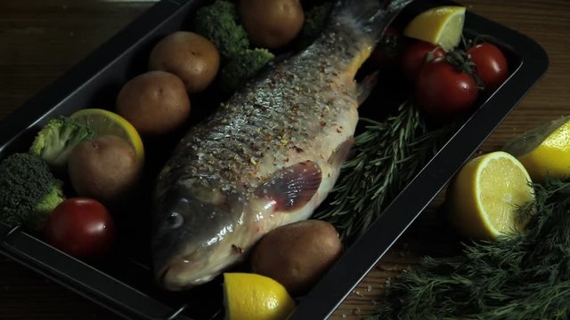 raw carp fish put on a baking tray, bake with vegetables, cooking process