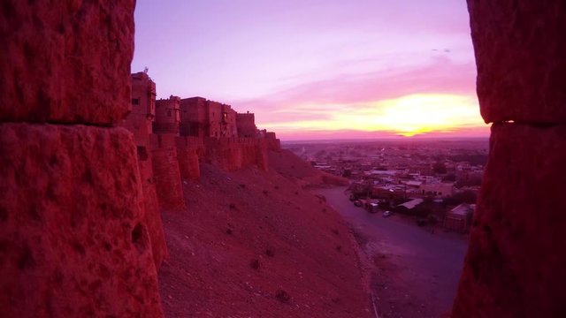 View through marlons on old citadel on hill and and small town on valley sunrise bird flies