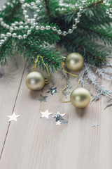 Christmas card with fir branch and golden balls, silver stars on white wooden background