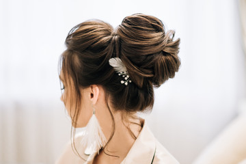 Pretty young girl.  Boudoir morning of the bride. Bride with luxurious hair and makeup. Accessories with feathers