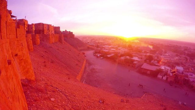 Ancient fort on hill and small desert town on valley in rays of sunrise