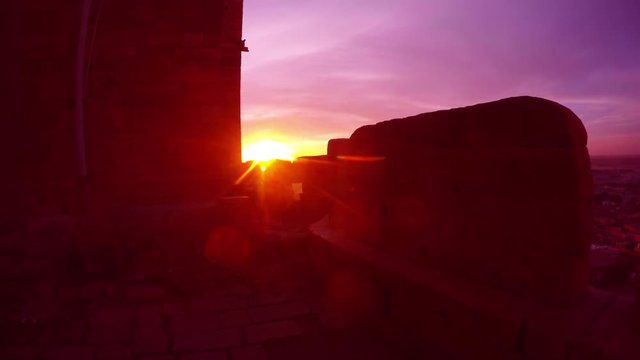 Rays of sunrise shine through marlons of ancient castle bird flies