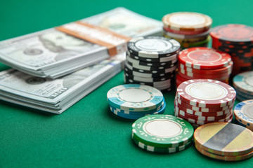 Concept of gambling in casino, sports poker. Gaming colored chips with cash cash dollars on green gaming table.