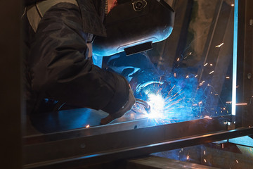 welder welds a metal frame for the power plant.