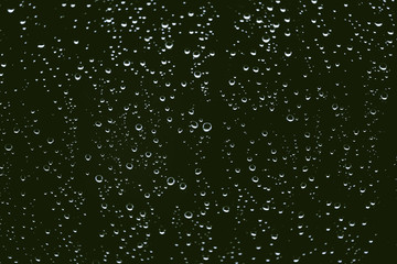 Naklejka na ściany i meble Dirty window glass with drops of rain. Atmospheric green background with raindrops. Droplets and stains close up. Detailed transparent texture in macro with copy space. Rainy weather.