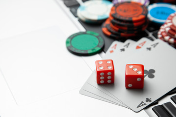 Online casino laptop. Laptop keyboard and chips with dice and playing cards on a green gaming table. Game addiction gambling. Poker online. Copy space for text.