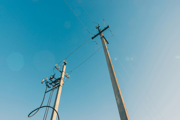 Power lines on background of blue sky close-up. Electric hub on pole. Electricity equipment with...