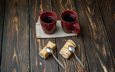 two mugs of coffee and two cakes on a wooden background