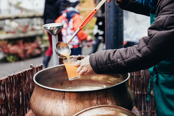 Pouring hot beverage called Punsch in German language into a glass with a huge kitchen spoon. Favourite hot drink at Christmas markets in Switzerland and in german-speaking countries. Keeping warm at 