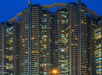 dichter gedrängter hoher Wohnkomplex in Hong Kong nach Sonnenuntergang zur blauen Stunde mit...