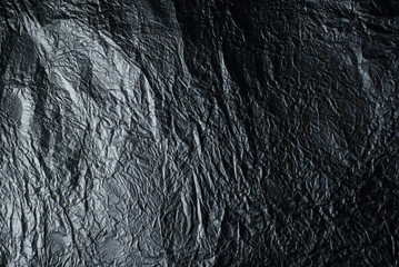 Thin wrinkled sheet of crushed tin aluminum silver foil background texture 