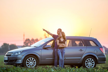 Young couple in love, slim attractive long -haired woman and handsome man pointing in distance...