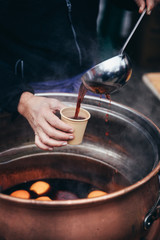 Pouring hot mulled wine, called Glühwein in German language, into a paper cup with a huge kitchen spoon. Favourite hot beverage at Christmas markets in Switzerland and in german-speaking countries. Ke