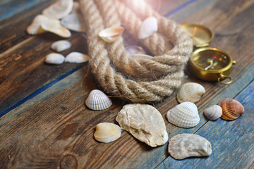 Fototapeta na wymiar Nautical background. Old deck with rope, compass and shells.