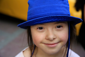 Cute smiling down syndrome girl on the background of taxi
