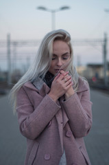 Young woman in the coat, walks on the city bridge during the windy weather. Urban autumn winter style