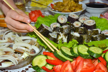 Tomatoes, cucumbers, radishes, sliced lie on a dish, dressed with olive oil for vegetarian food on a festive table.