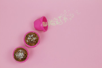 Banana muffins sprinkled with sesame in pink baking cups on the pink background.