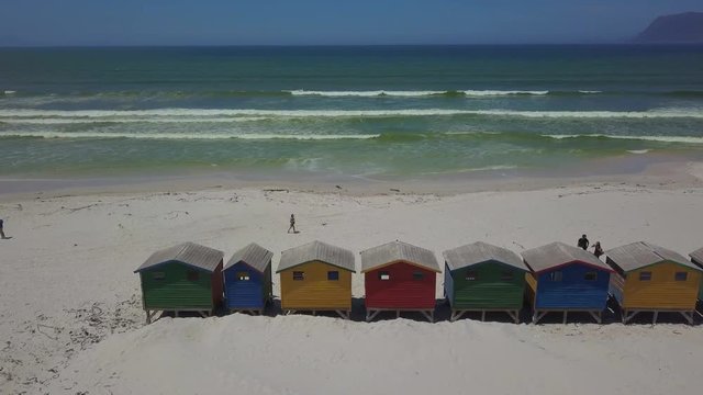 Colourful wooden beach huts with unidentifiable people as seen from above on the beach at Muizenberg near Cape Town, South Africa.