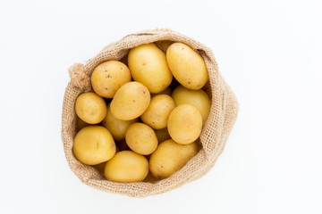 Sack of fresh raw potatoes on wooden background, top view