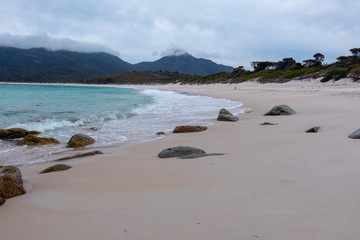 The beach at Wineglass Bay, Freycinet National Park, Tasmania on a cloudy day with rocks in the foreground