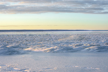 Winter landscape with a frozen river covered with snow and ice