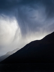 A silhouette of a mountain with rain cloudy hanging over it