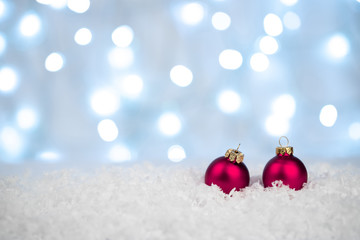 Red Christmas balls on snow with defocused silver and white lights