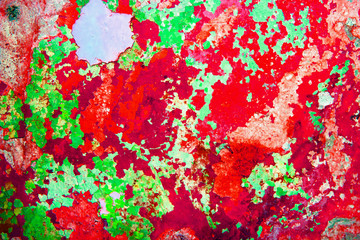 detail of the cracked paint on the concrete wall. abstract texture of concrete and old cracked paint, red and green