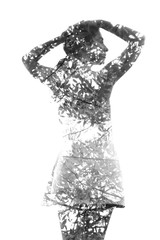 Double exposure. A healthy girl with her hands on her head combined with photograph of tropical plants with sun shining through the leaves, black and white