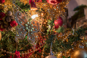 Close up of a lighten up Christmas tree decoration, with gold, red and silver balls, along with red...