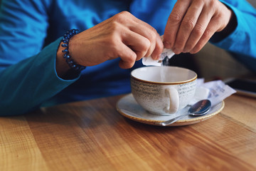Fototapeta na wymiar closeup womans hands with sugar stick and tea