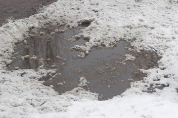 Winter puddles and snow slush on road