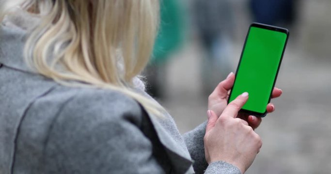 Woman hands holding cellphone with green screen