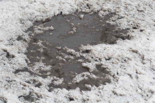 Winter puddles and snow slush on road