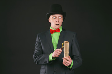 Shocked spy secret agent is looking on a top secret documents in his hand through magnifying glass isolated on the black background.