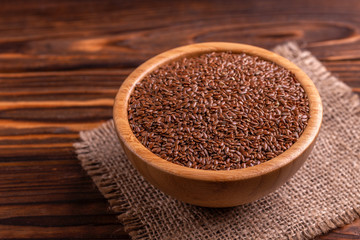 Raw flax seeds in wooden bowl with burlap napkin