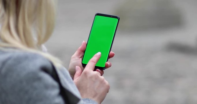 Woman hands holding cellphone with green screen