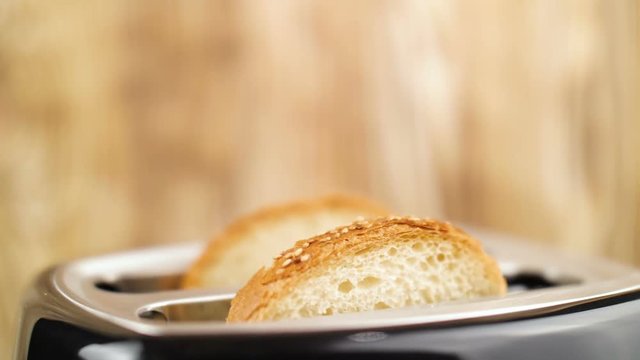 Fresh sliced bread falling in toaster in slow motion. Close up.