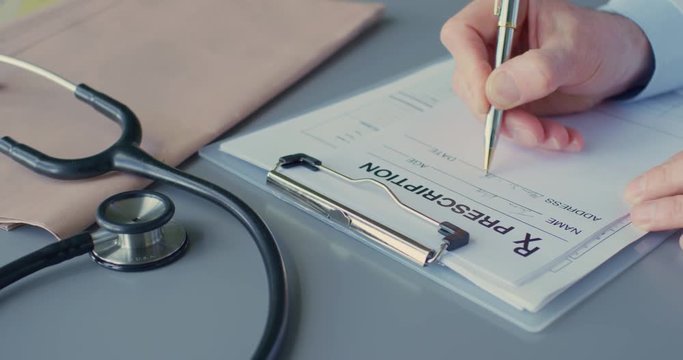 Medical Professional Writing Rx Prescription On Clipboard At Desk 4K